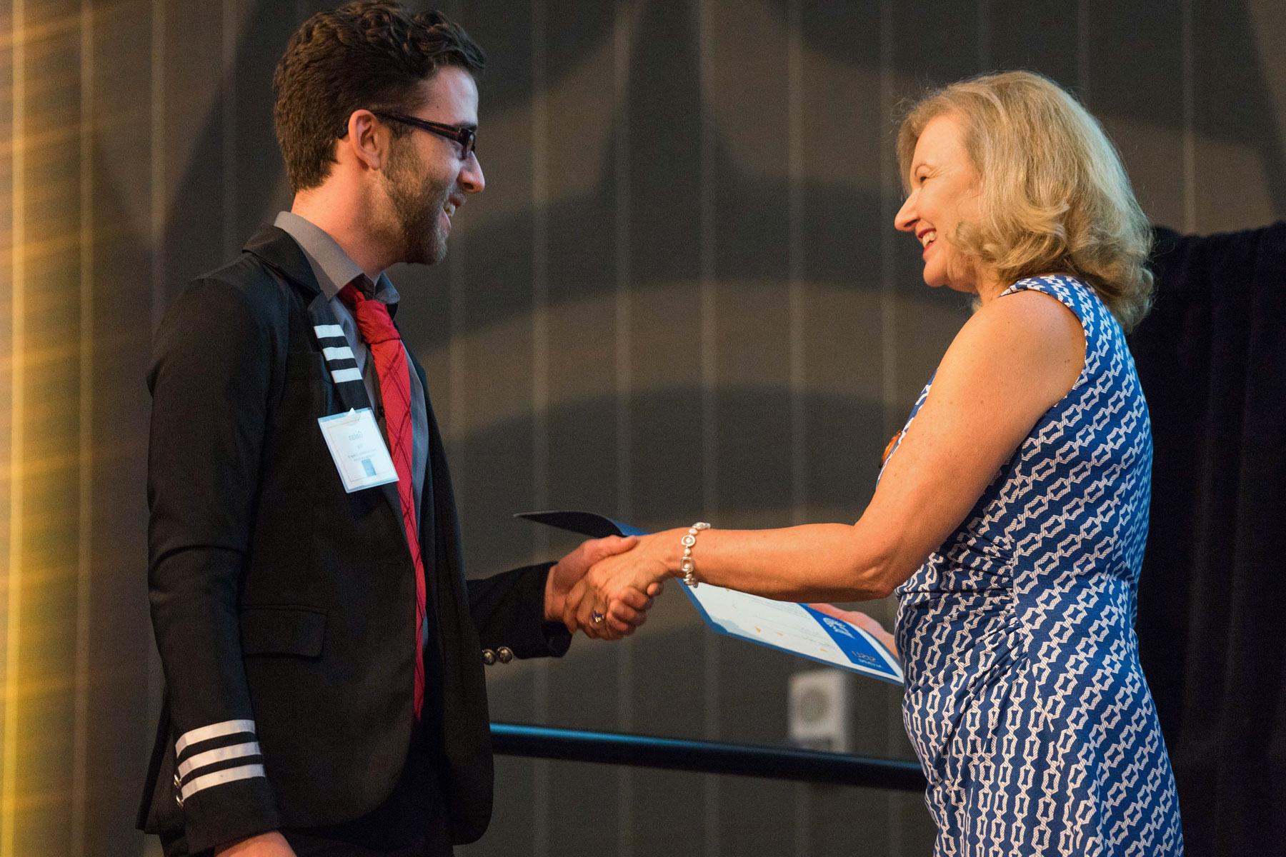 A staff member shakes the hand of a scholarship recipient. 