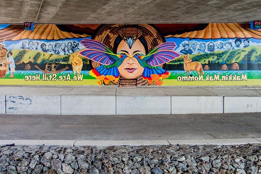 A colorful mural under a bridge.